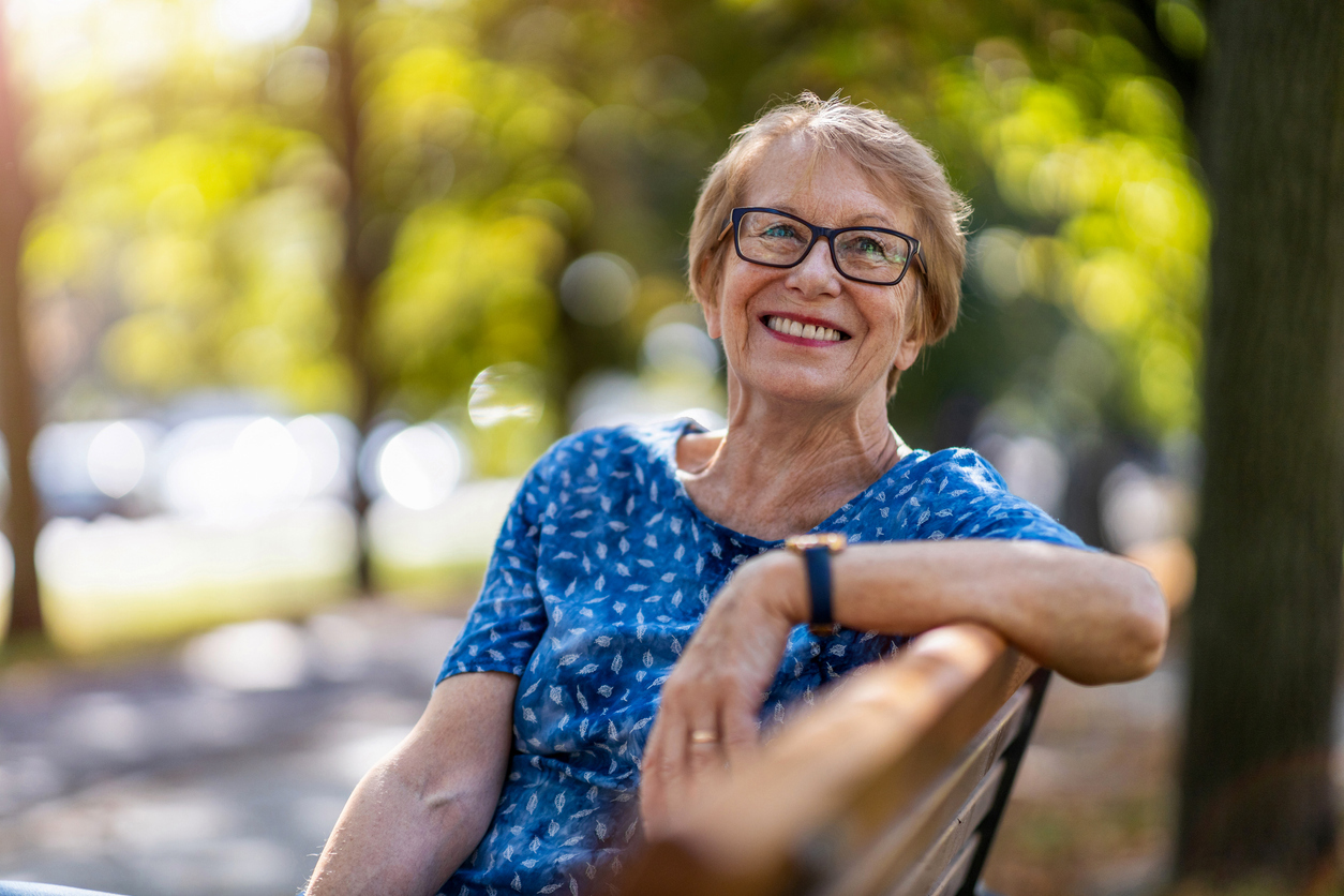 Mature woman sitting on a bench in the sun. 