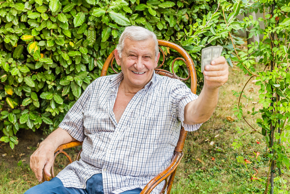 old happy man holds up playing cards. 