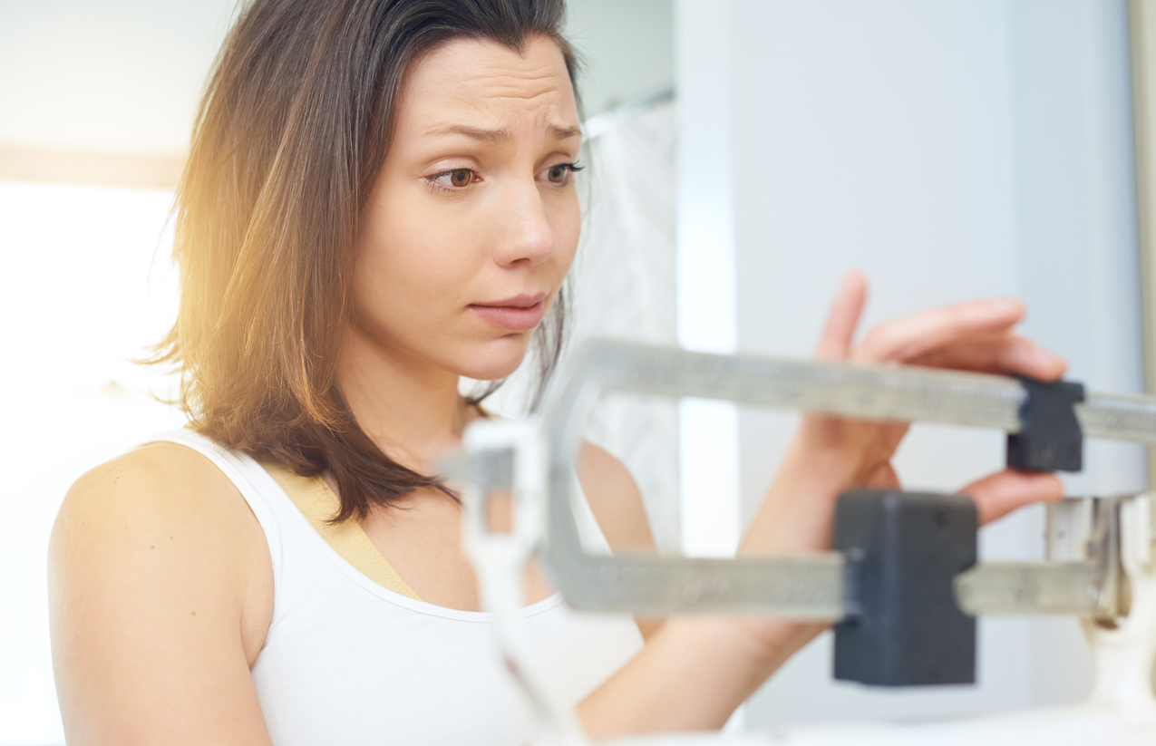 Woman weighing herself on a scale. 