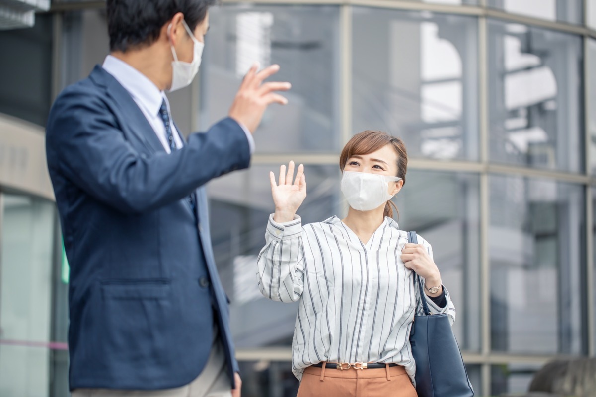 Asian woman and Asian man both waving and wearing masks