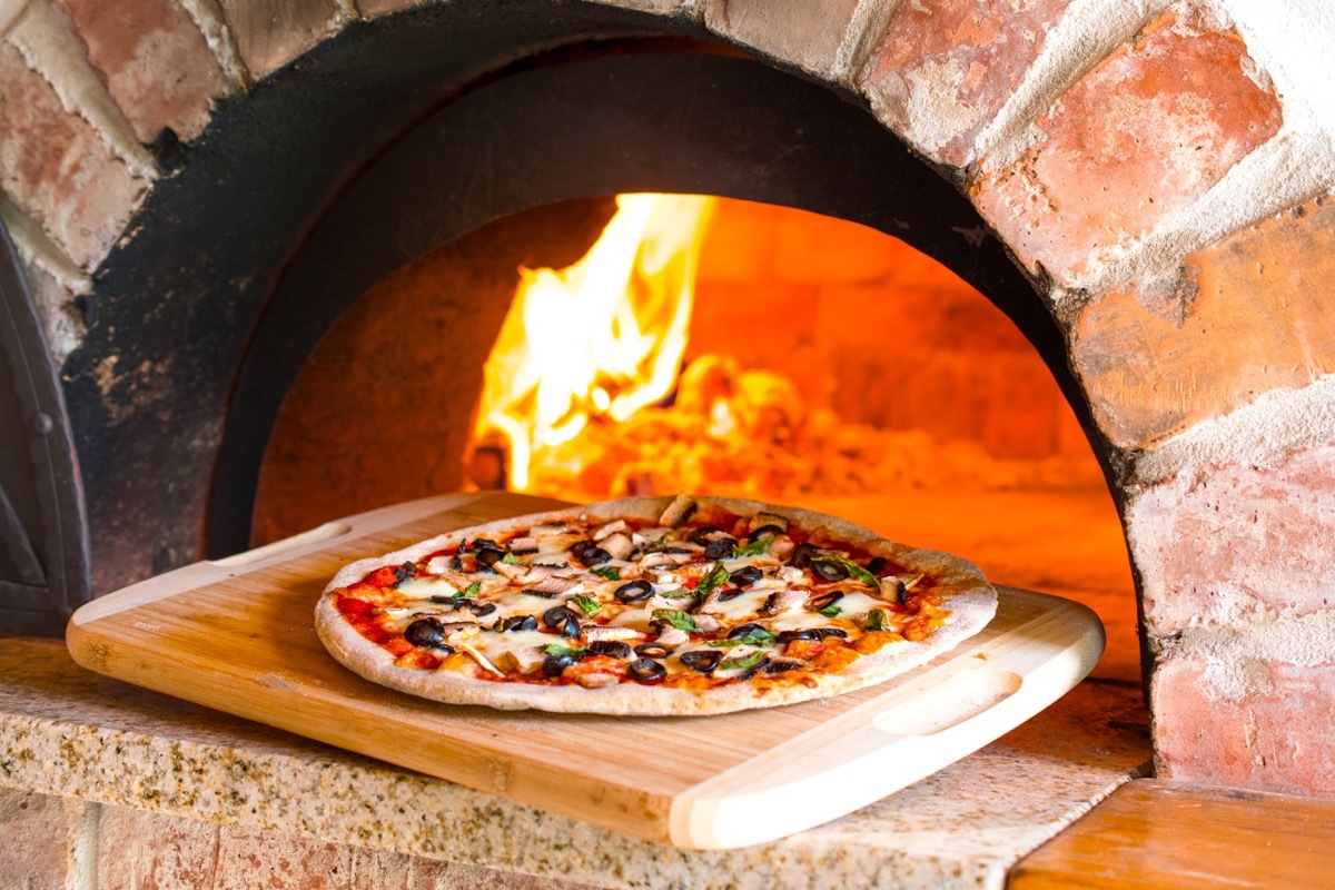 a pizza outside a brick oven, pizza oven