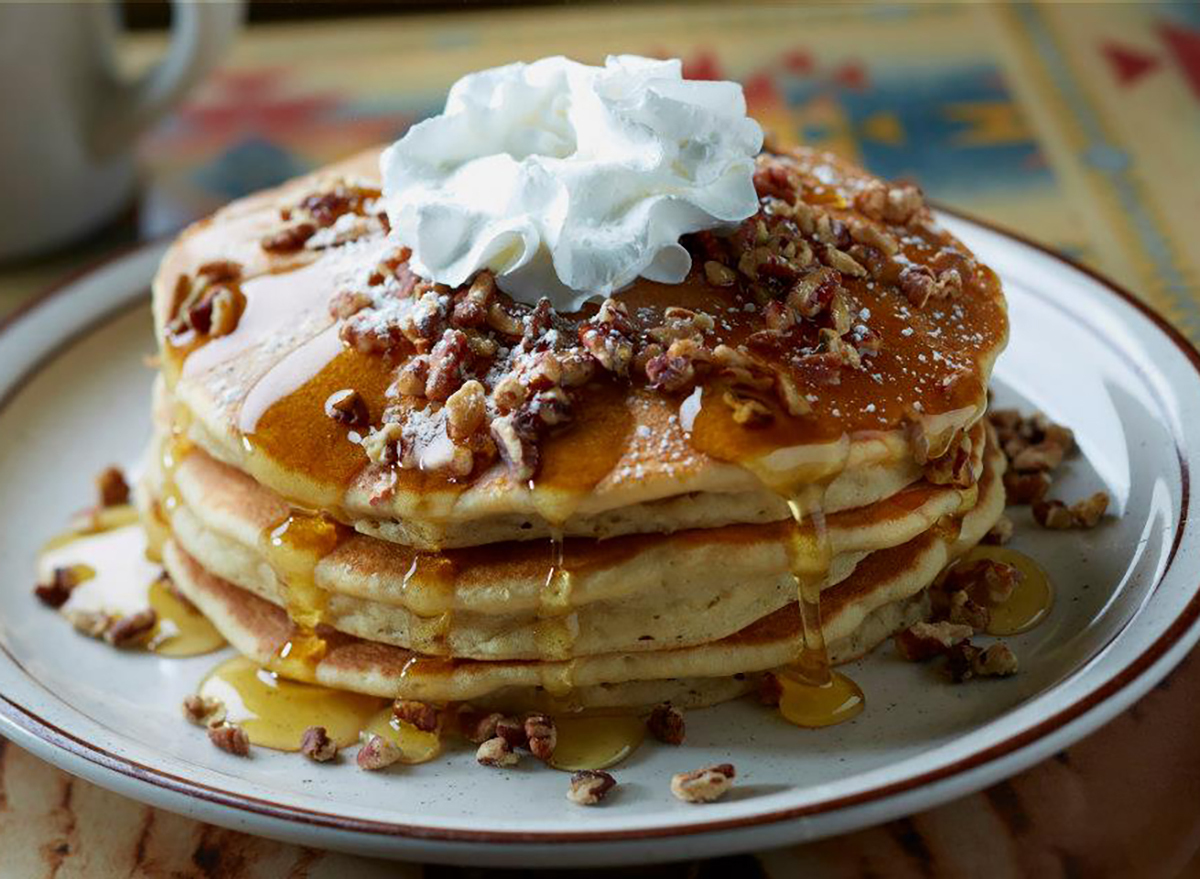 stack of pancakes with nuts and whipped cream