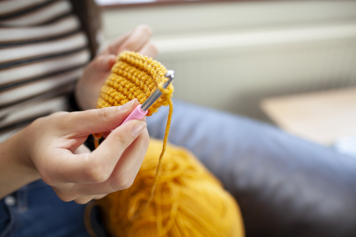 Close-up of woman crocheting with yellow wool