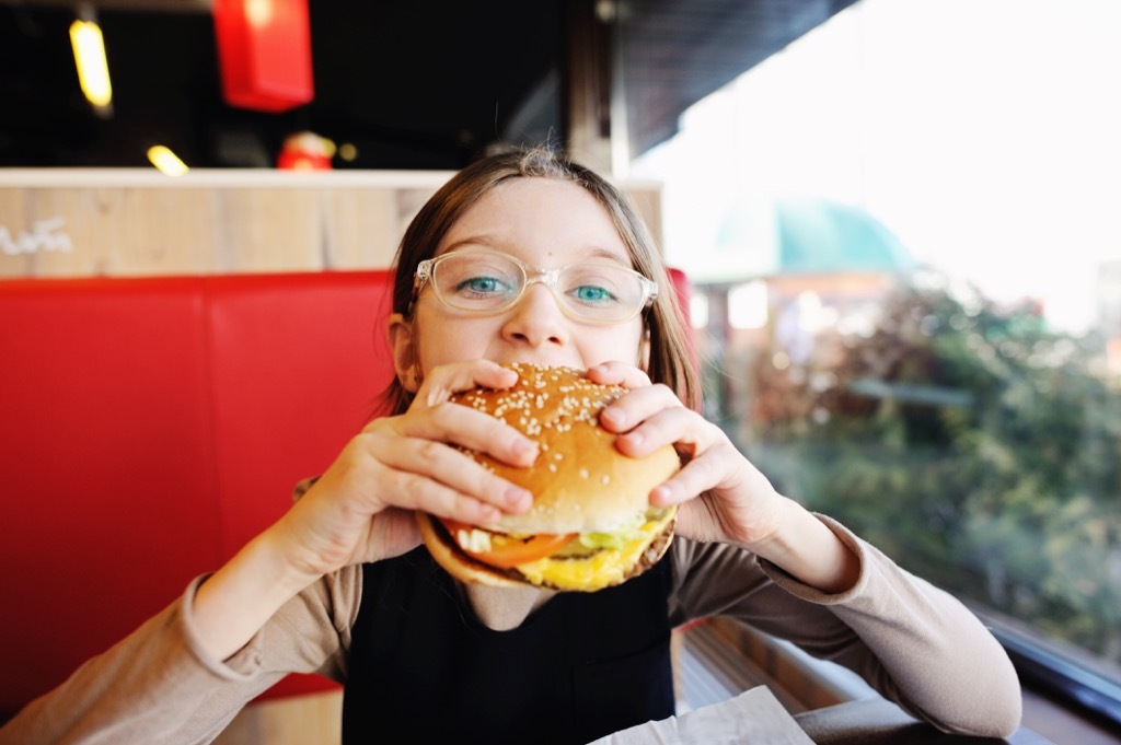 teen eating burger at restaurant