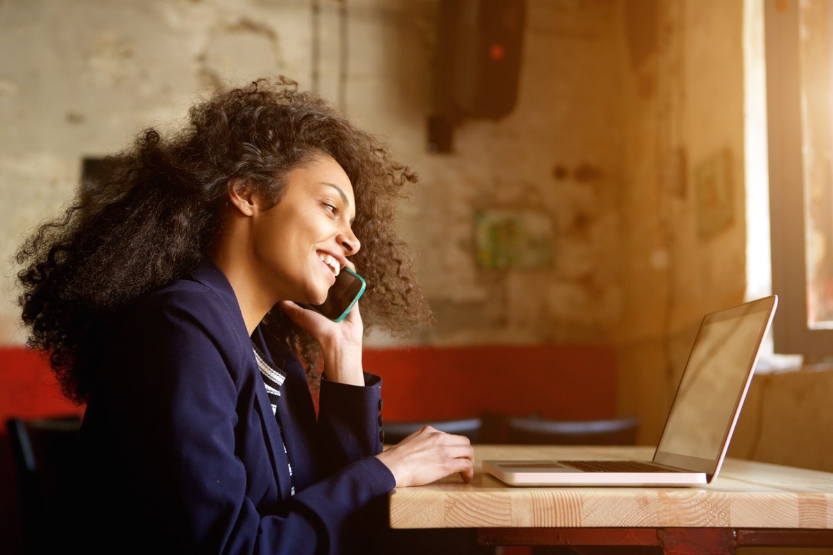 Woman on phone call while looking at her laptop