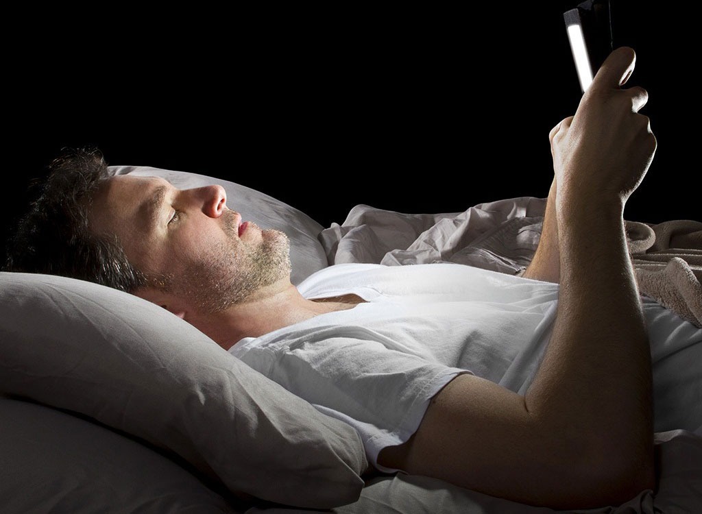 Man laying in bed on phone