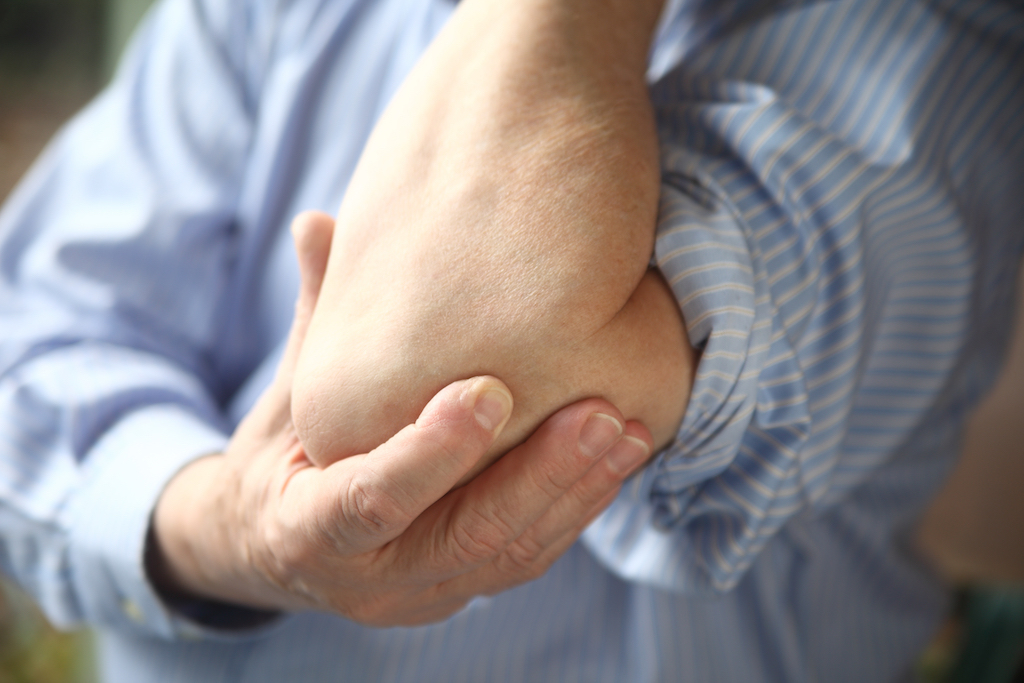 man holding his elbow because of tennis elbow pain men's health concerns over 40