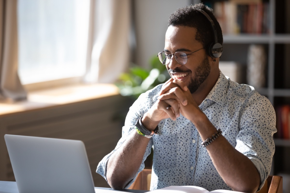 young black man smiling and chatting on his laptop