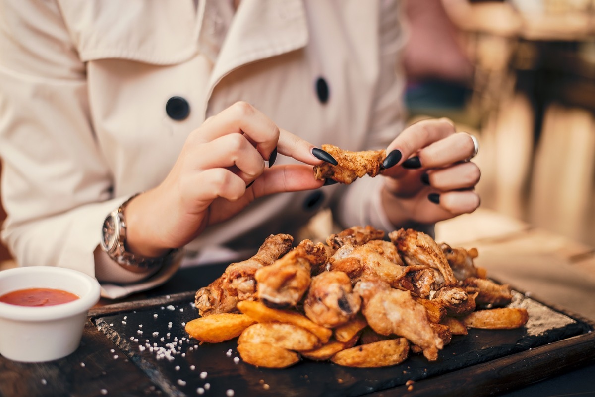 woman with black nails eating chicken wings