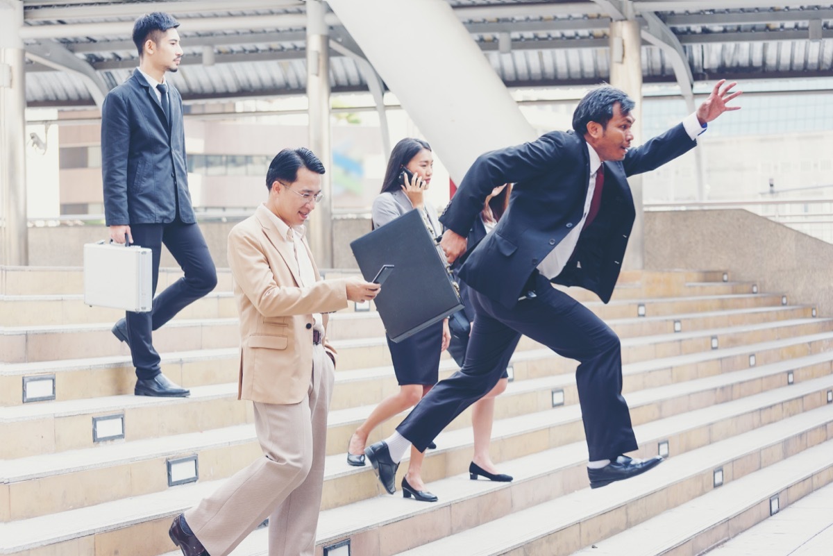 Asian businessman races down steps, passing three other business people, etiquette over 40