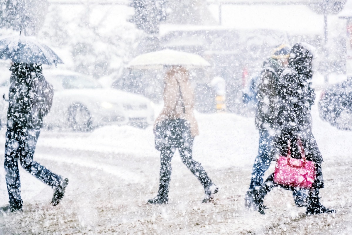 Pedestrians crossing the street on a snowy day.