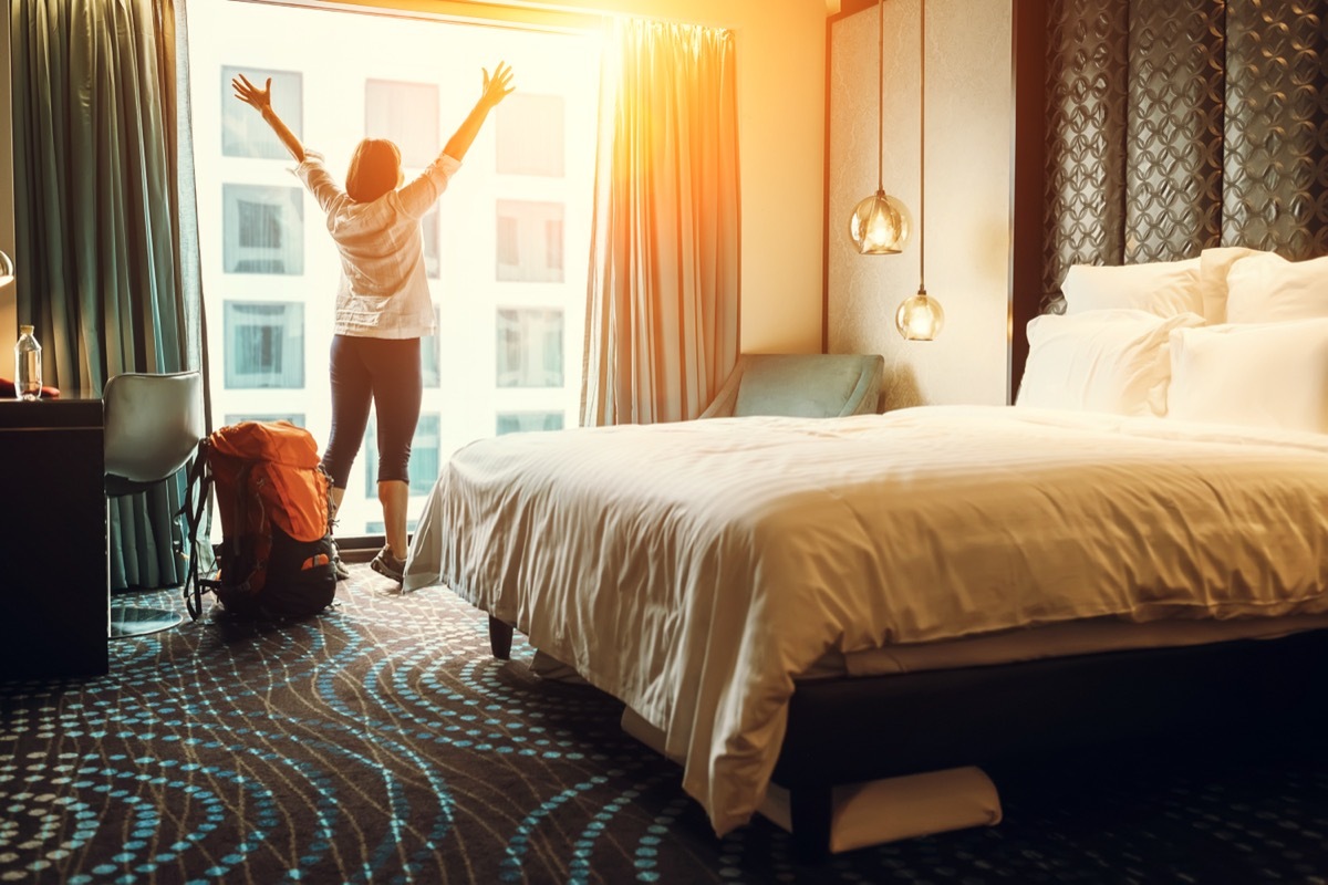 Woman standing with arms raised in the window of a hotel room