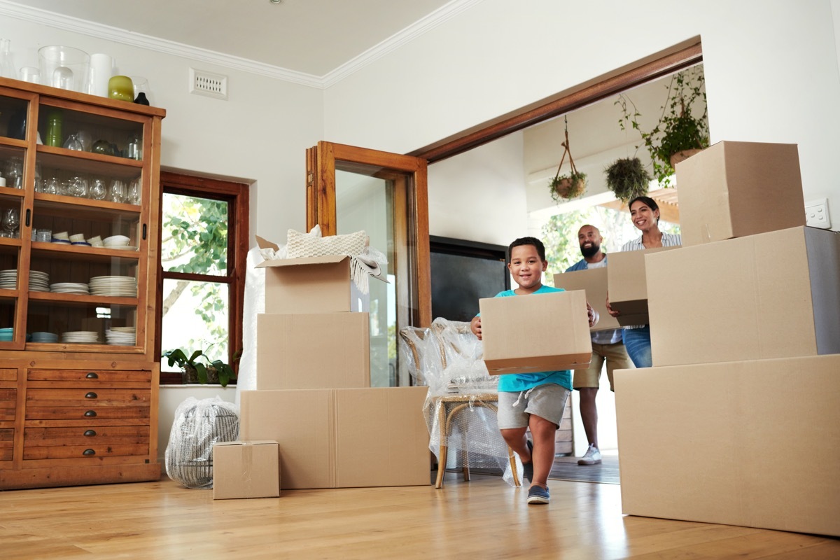 Shot of young family of three carrying moving boxes into their new home