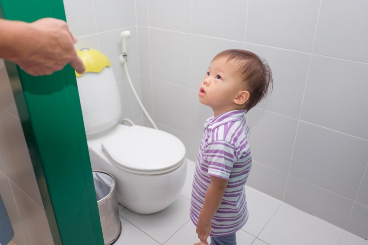 parent's hand on door opening bathroom to tell son to use toilet