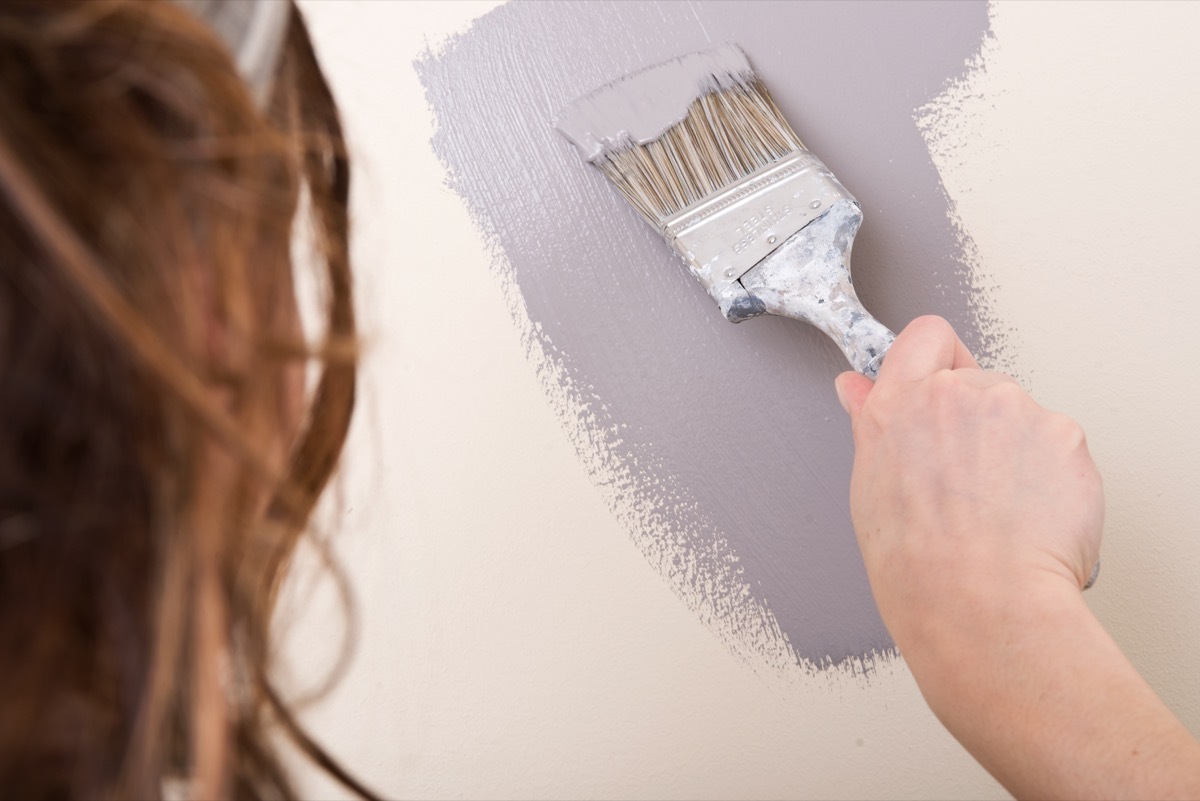 Woman painting the walls gray