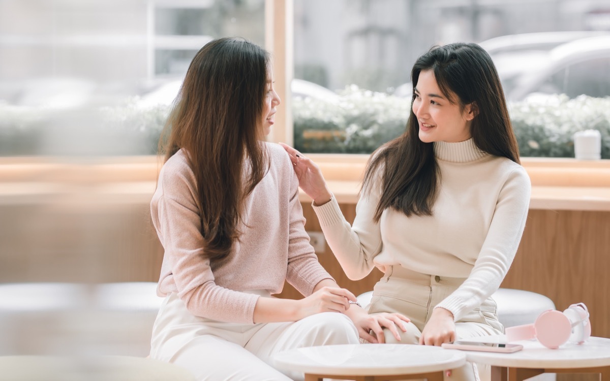 women smiling and talking together in coffee shop. Lifestyle and Winter Concept.