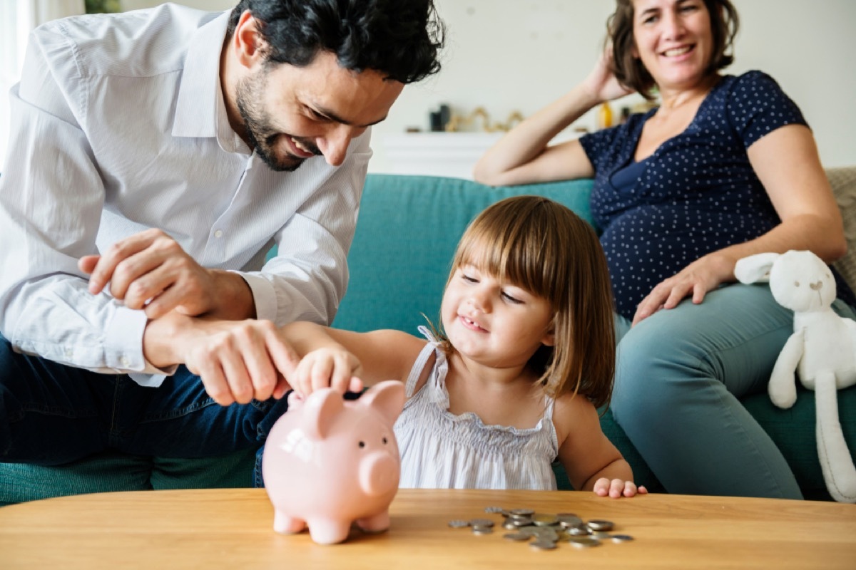 young girl putting coins in piggy bank, skills parents should teach kids