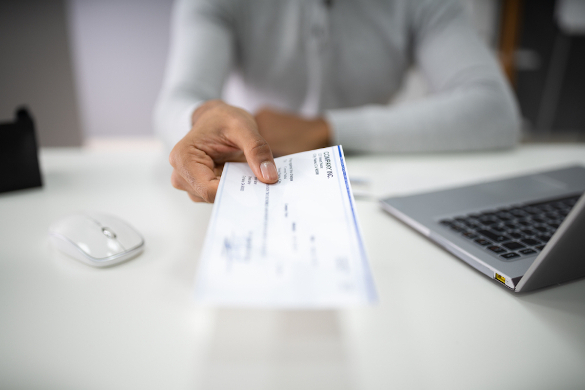 closeup of woman's hand handing over a paycheck