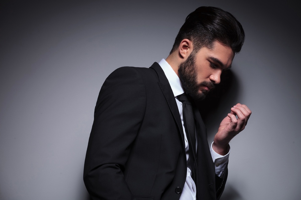 young man in suit looking at his fingernails