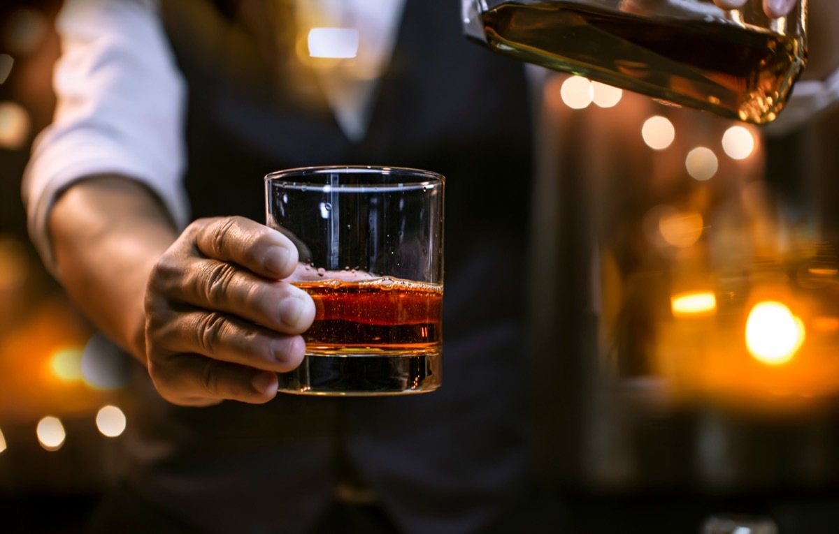 man holding whiskey bourbon in clear glass