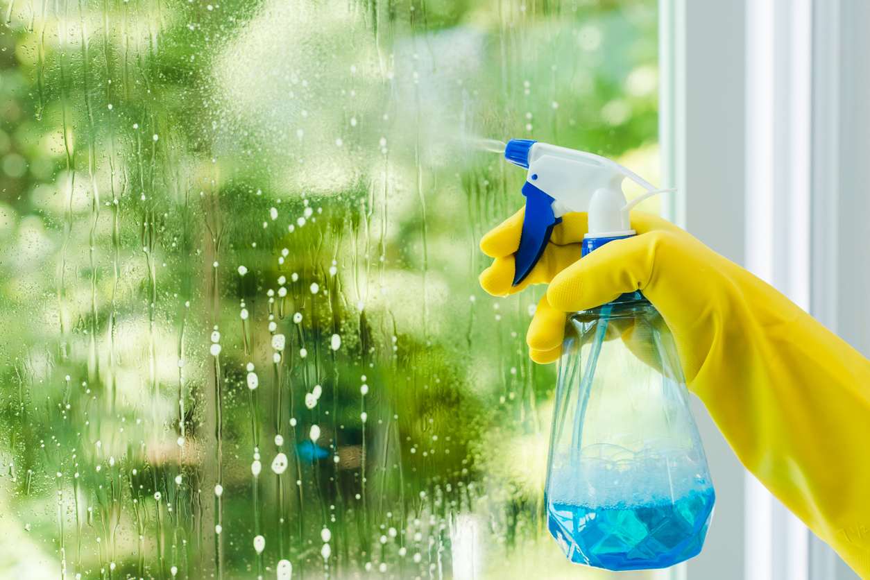 Hand spraying window cleaner on a window.