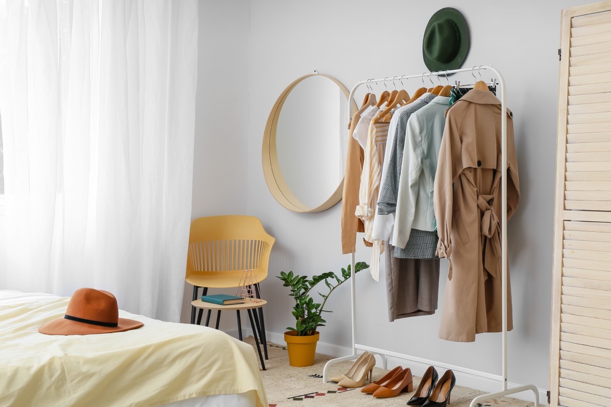 small bedroom ideas - hanging rack with clothes on it next to a bed