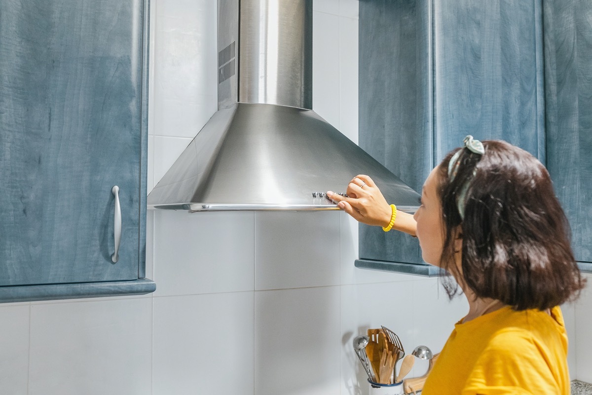 Woman turn on exhaust ventilation in the kitchen