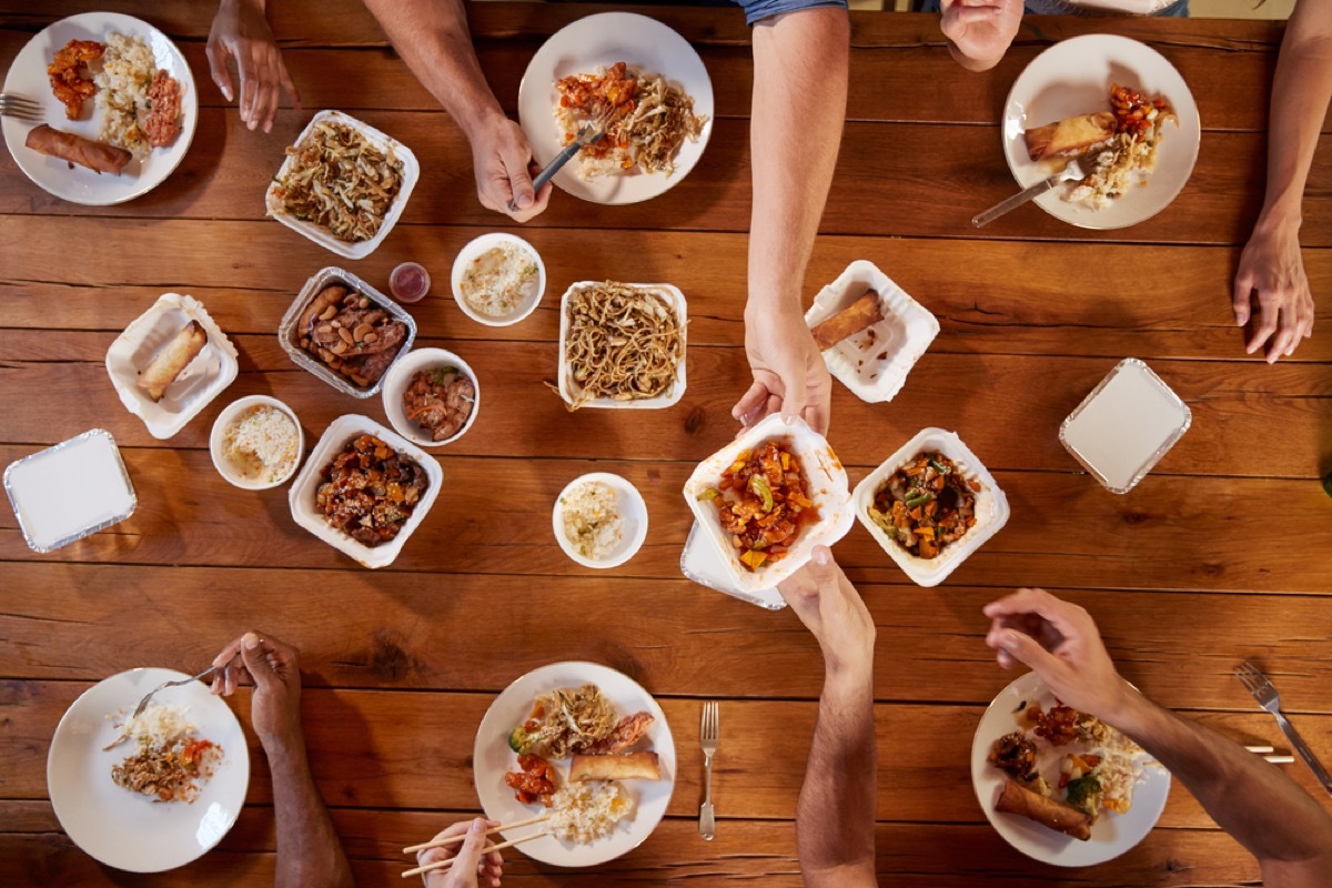 people reaching across table for food, etiquette mistakes