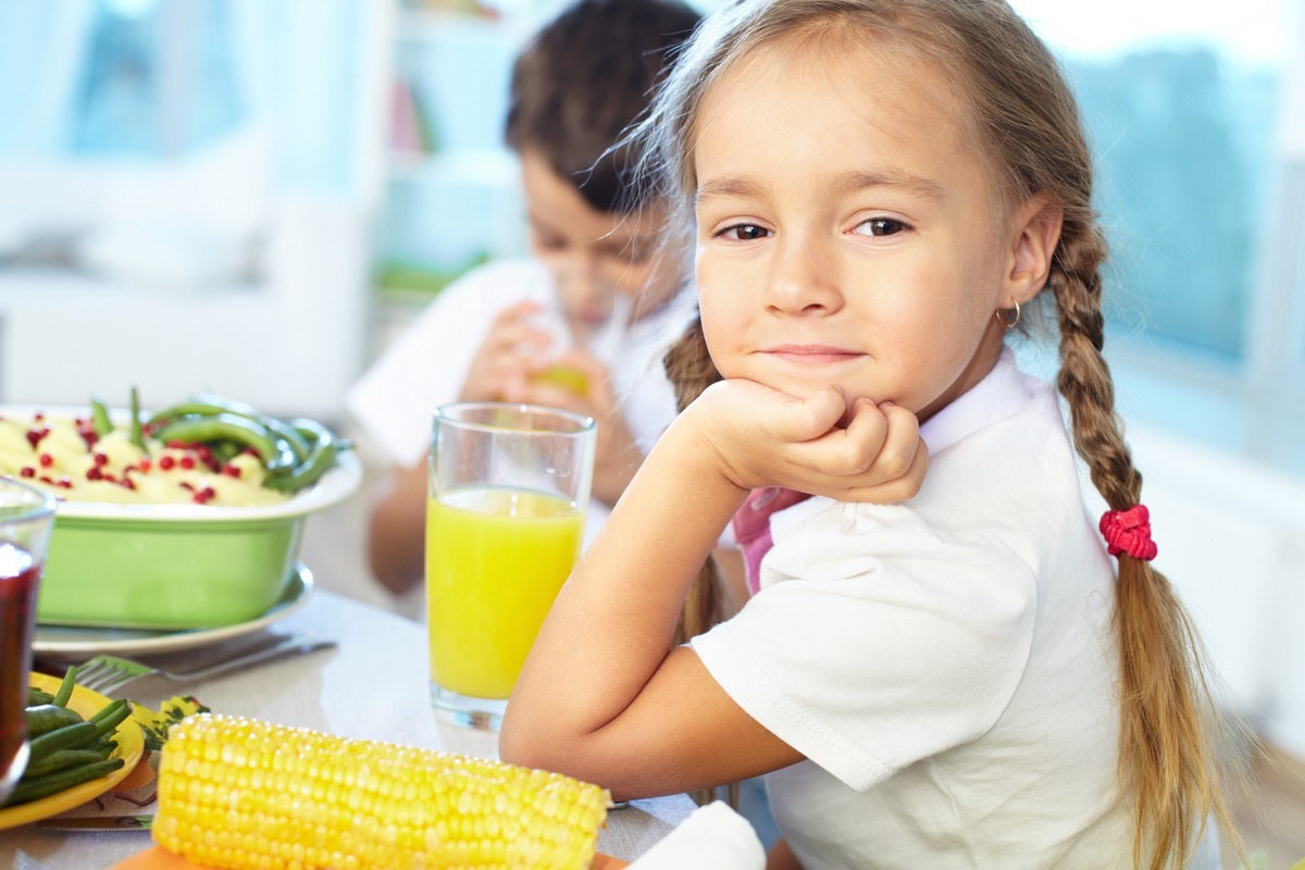 Portrait of happy girl sitting at festive table and looking at camera