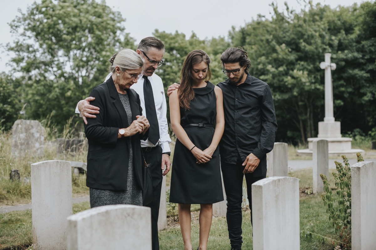 family wearing black to a funeral in a cemetery