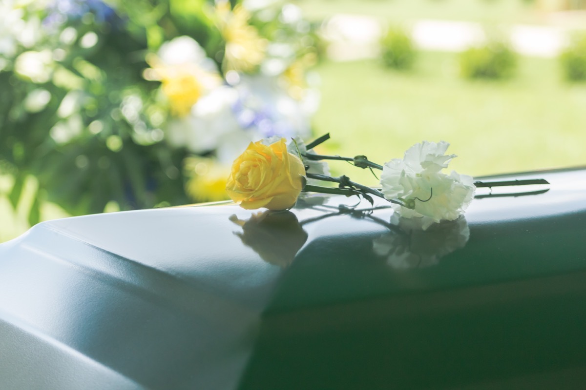 A closeup of flowers atop a funeral casket outdoors, state fact about georgia