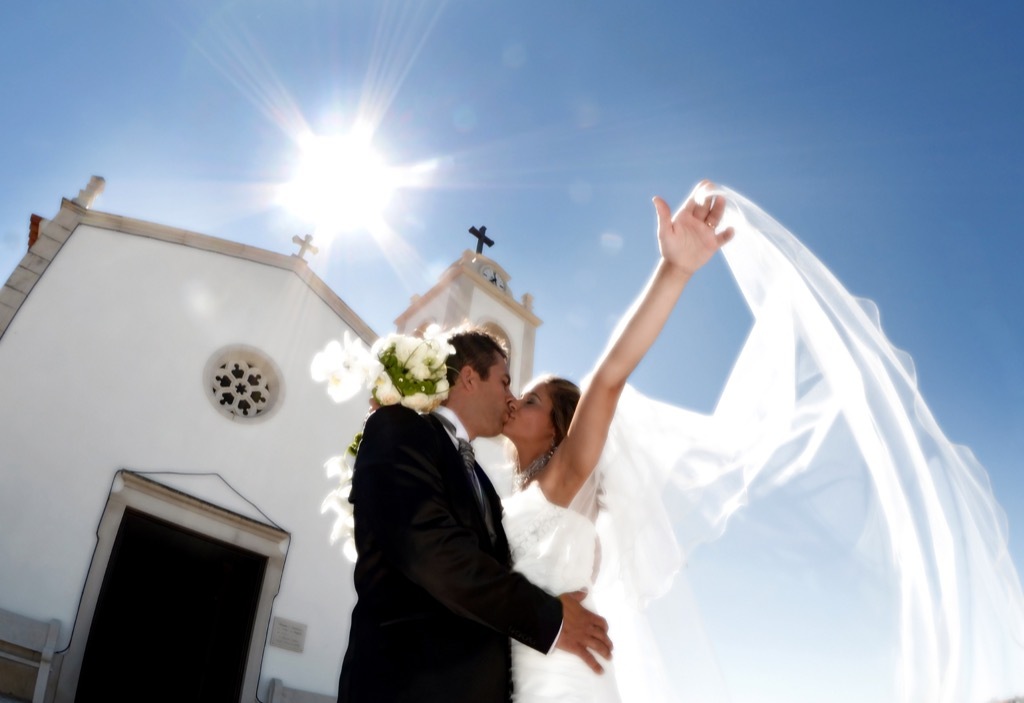 couple kissing outside church 20 Old-Fashioned Wedding Traditions That Nobody Does Anymore