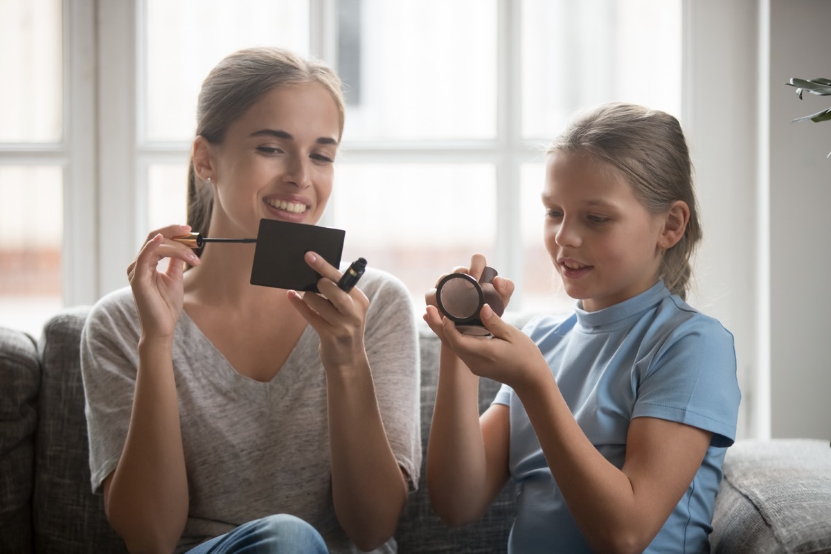 white mom and daughter applying cosmetics