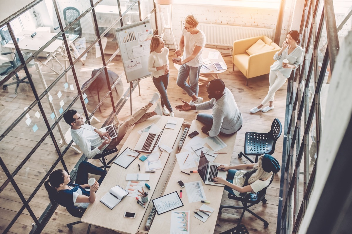 an overhead shot of office employees in a glass-walled conference room