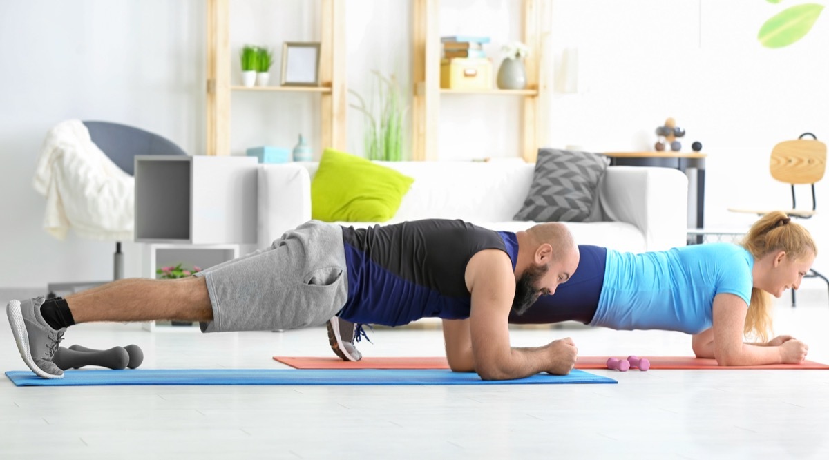 Couple doing planks together in their living room