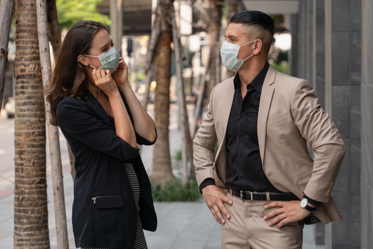 man and woman talking while wearing masks