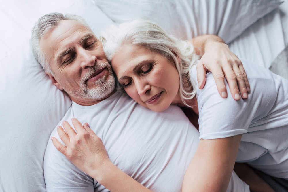 A senior couple sleeping in bed