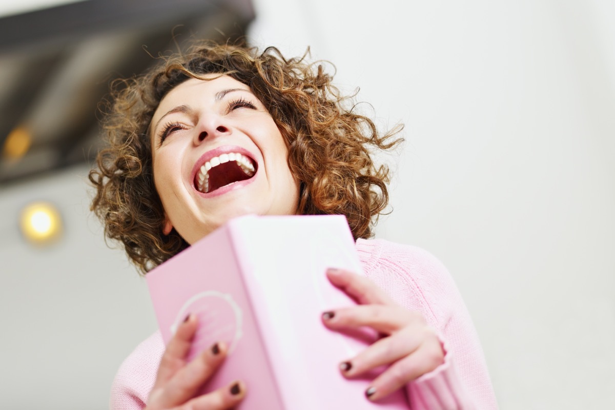 woman laughing while reading a book {Conquer Negative Thinking}