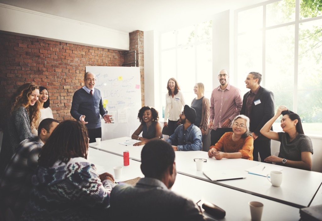 smiling boss in a brick-walled conference room with laughing employees