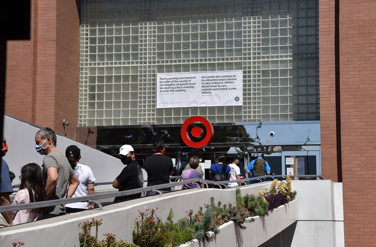 A sign reads face masks required as customers line up to enter a Target store during coronavirus in Glendale, California, in April 2020