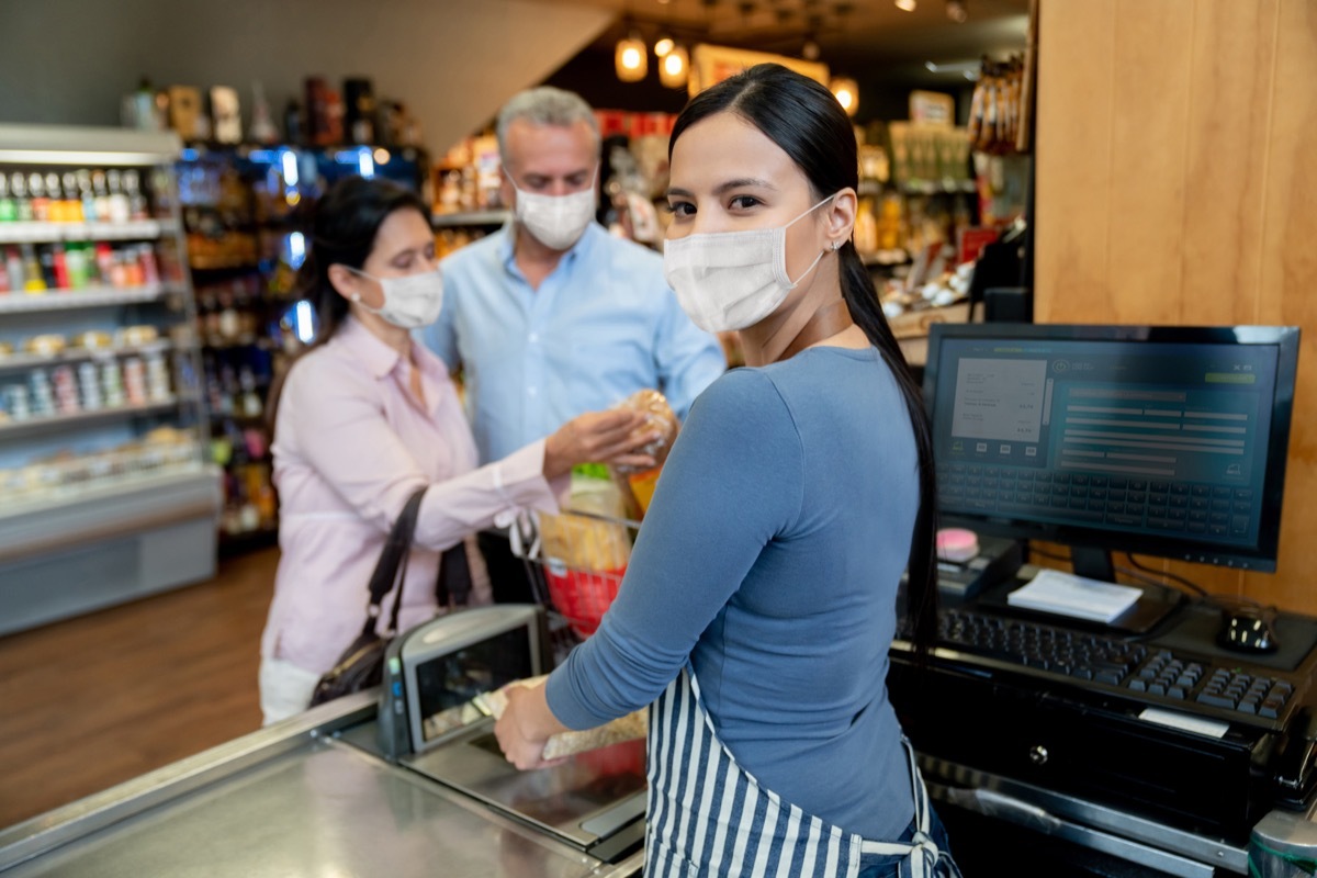 Cashier working at the supermarket wearing a facemask while scanning products