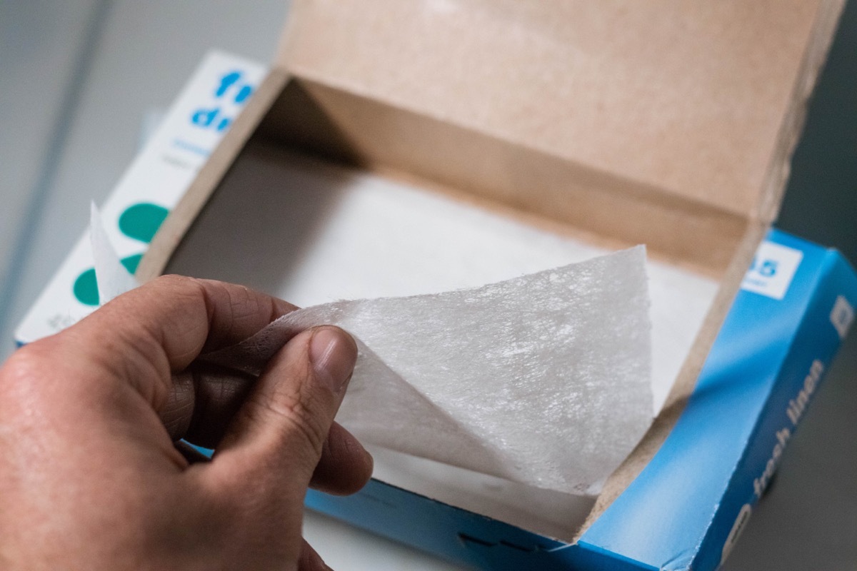 Cumberland, Rhode Island/ USA- March 31, 2019 a box of laundry dryer sheets being placed on top of a dryer with the rest of the laundry cleaning products.