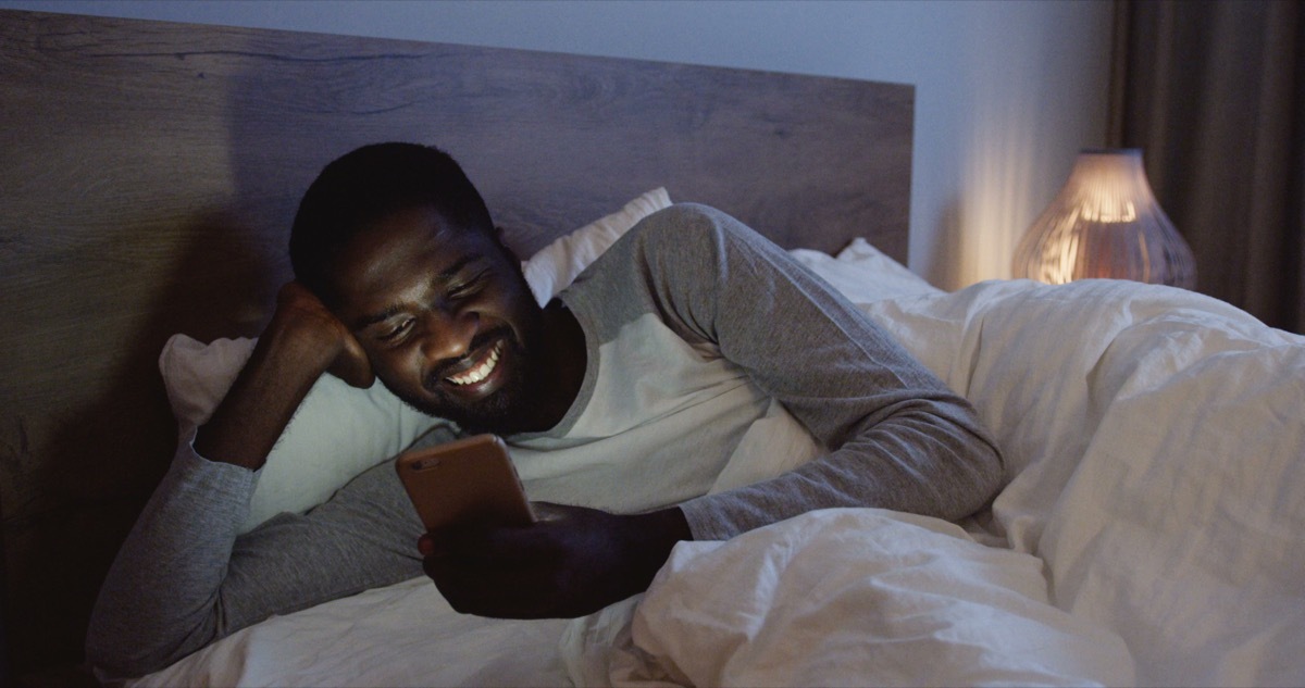 Man texting in bed not sleeping at night