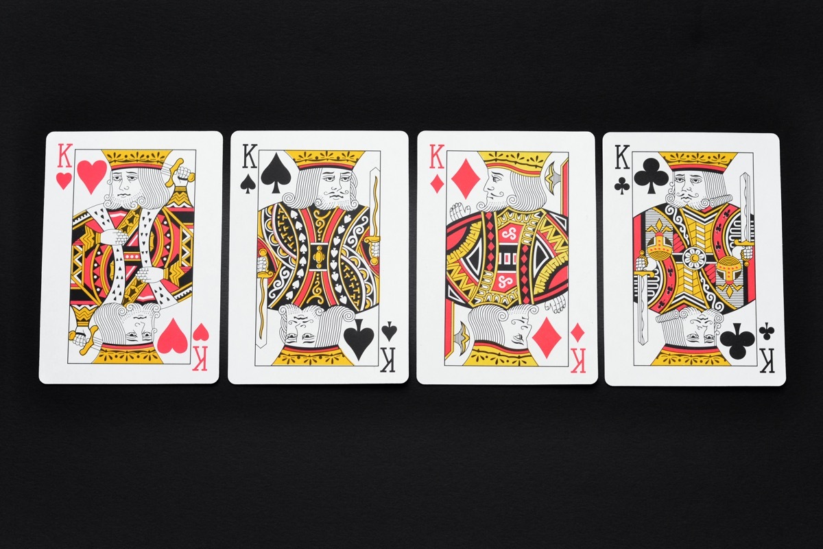 Close up of the four kings in a deck of playing cards on a black background.