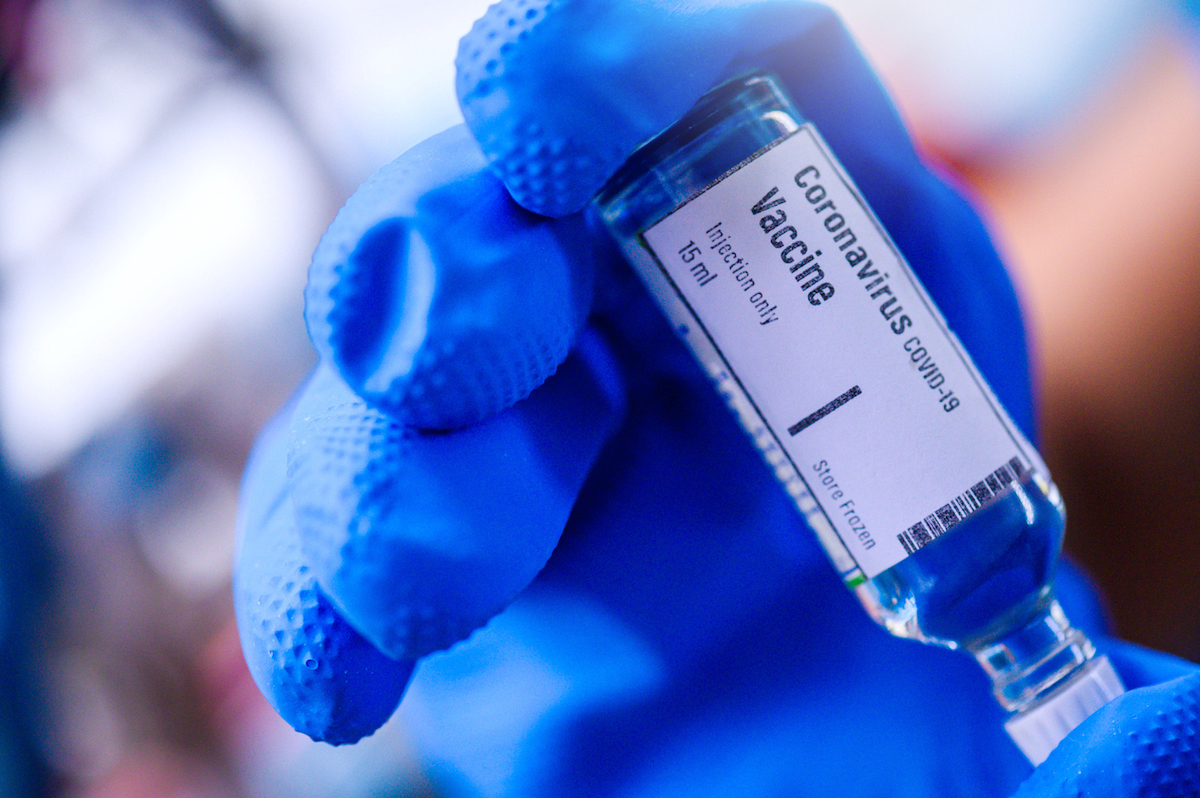 Hand holds Coronavirus Covid-19 Vaccine glass bottle