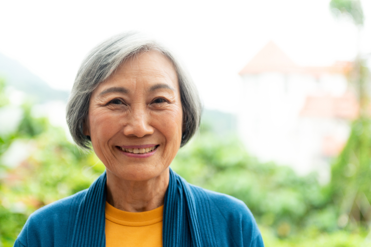 older woman with gray hair smiling outside