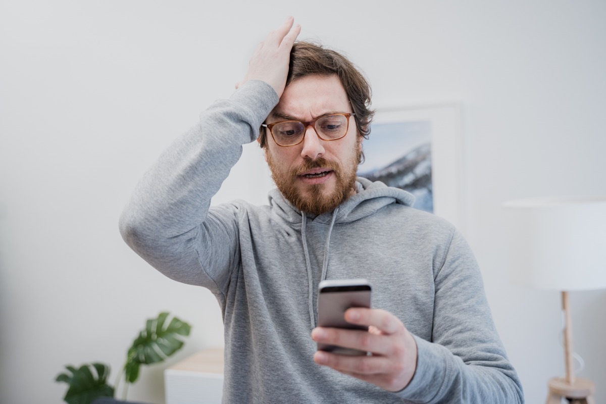 Annoyed frustrated male reading bad news on the cellphone