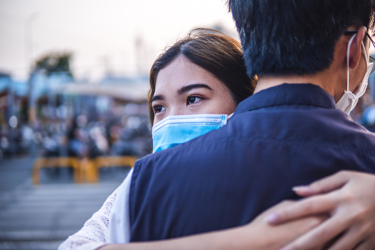 Young millennials hugging and wearing a protective face mask