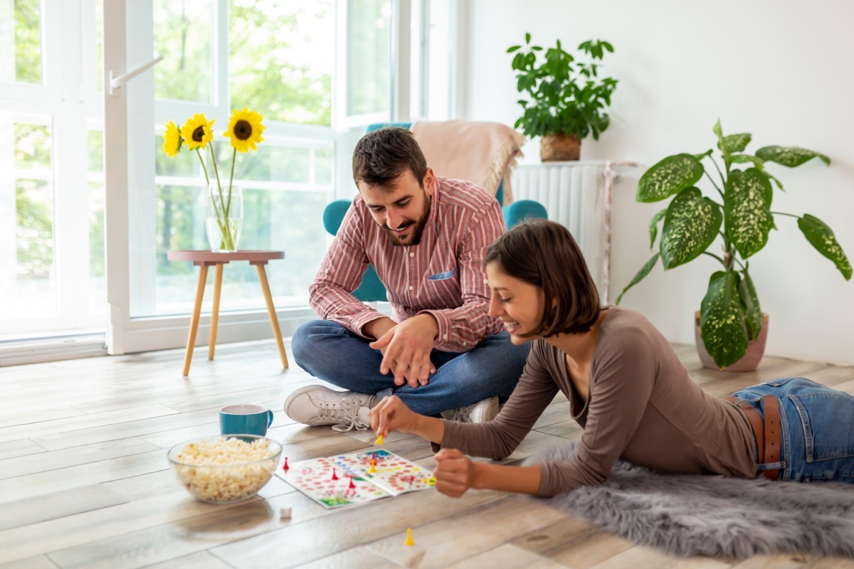 couple playing a board game at home on the floor while eating popcorn