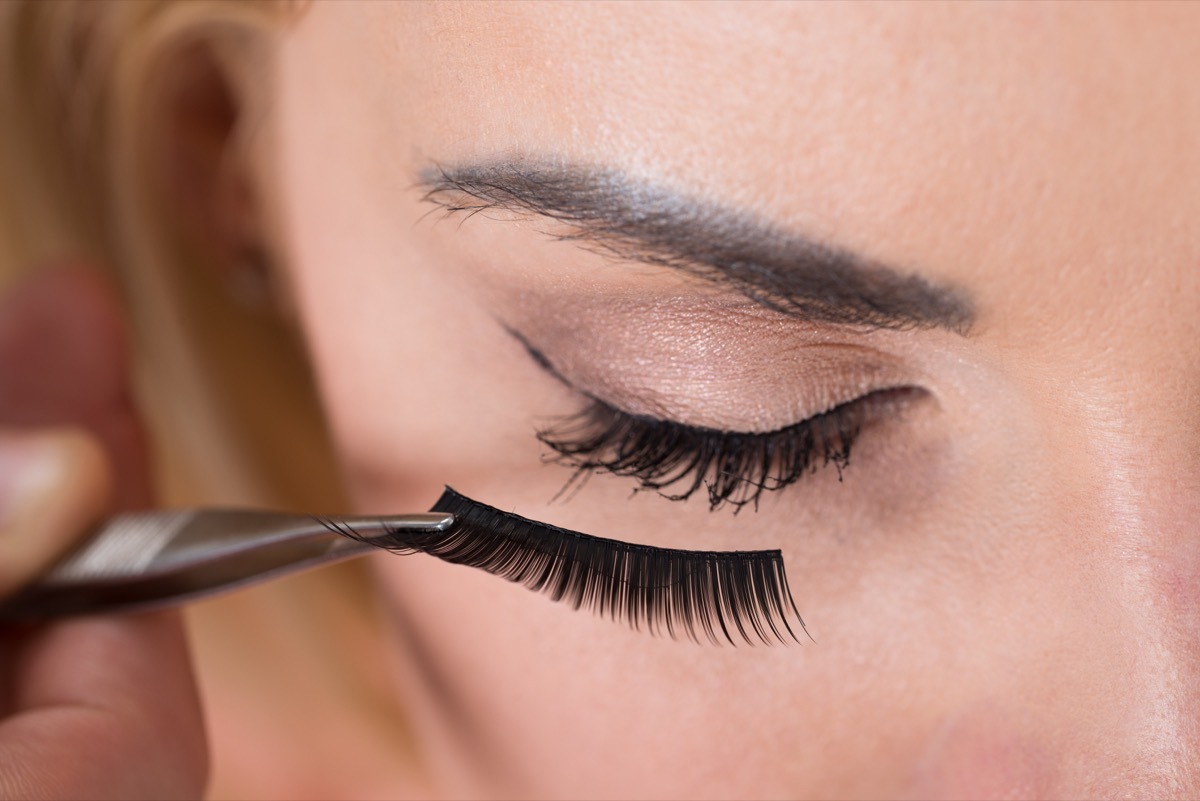 Close-up of false eyelashes being put on woman's eye